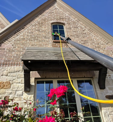 Cleaning a window of a brown brick home with a five stage filtration water pool